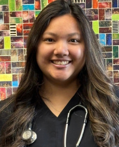 Woman in front of colorful tiled wall background, wearing a stethoscope